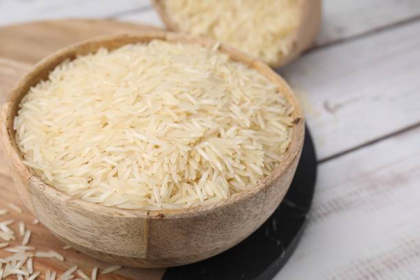 istock Raw rice in bowl on light wooden table, closeup. Space for text 1806141989