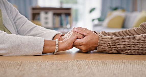 Senior couple, holding hands and closeup on table for care love or retirement support, compassion or trust. Old people, partnership and fingers for difficult news or loss comfort, solidarity or help