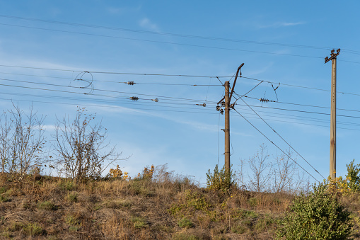 Electrified railway pole on blue sky background. Electric power supply lines on pillars along railway track. Technology of catenary wires. Details structure of voltage system. Equipment of railroad.