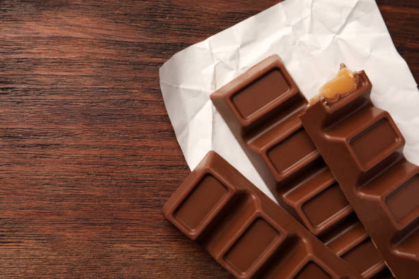 istock Tasty chocolate bars on wooden table, top view. Space for text 1806153595