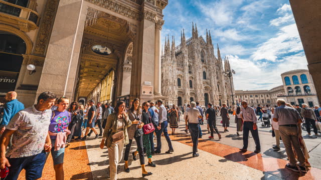 Time lapse of Crowd of People tourism walking and sightseeing attraction at Milan Cathedral (Duomo di Milano) with perfect blue sky and cloud in Milan, Italy