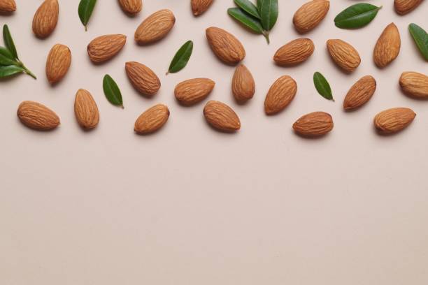istock Delicious almonds and fresh leaves on beige background, flat lay. Space for text 1806171142