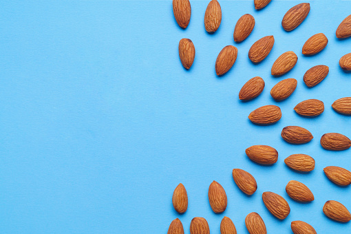 Delicious raw almonds on light blue background, flat lay. Space for text