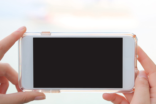 Person holding a smartphone with blank space to place advertising, advertisements. Billboard
