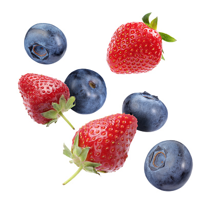 Fresh ripe blueberries and strawberries falling on white background