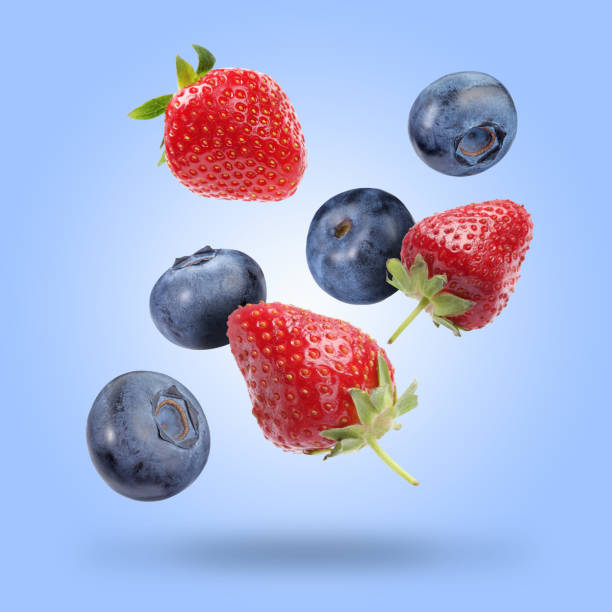 istock Fresh ripe blueberries and strawberries falling on pastel blue background 1806180512