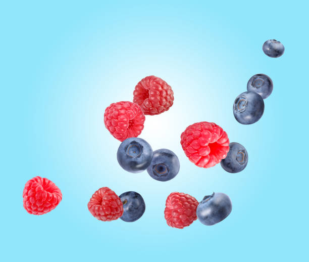 istock Fresh ripe blueberries and raspberries falling on light blue background 1806182156