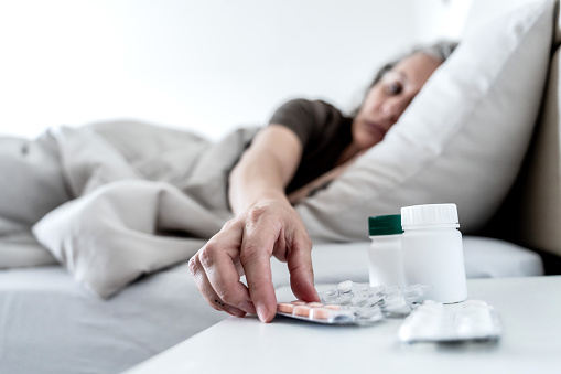 Depressed woman lying in her bed. Remedy, pill, medicine capsule