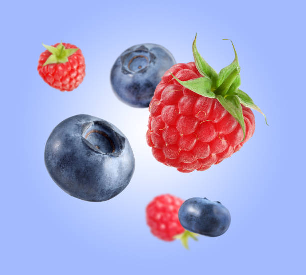 istock Fresh ripe blueberries and raspberries falling on pastel blue background 1806182175