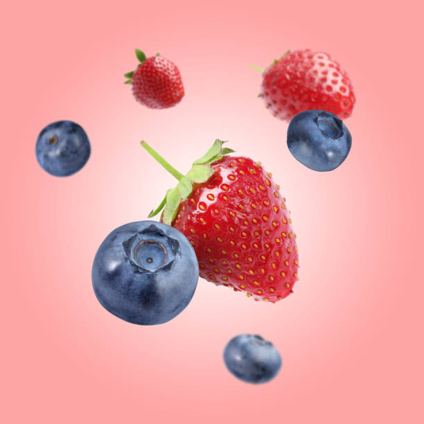 istock Fresh ripe blueberries and strawberries falling on coral background 1806182182