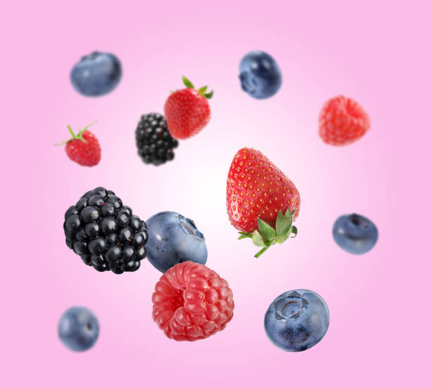 istock Fresh ripe blueberries, strawberries, raspberries and blackberries falling on pink background 1806183309