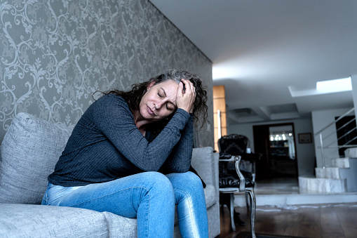 Depressed woman sitting on the sofa in the living room