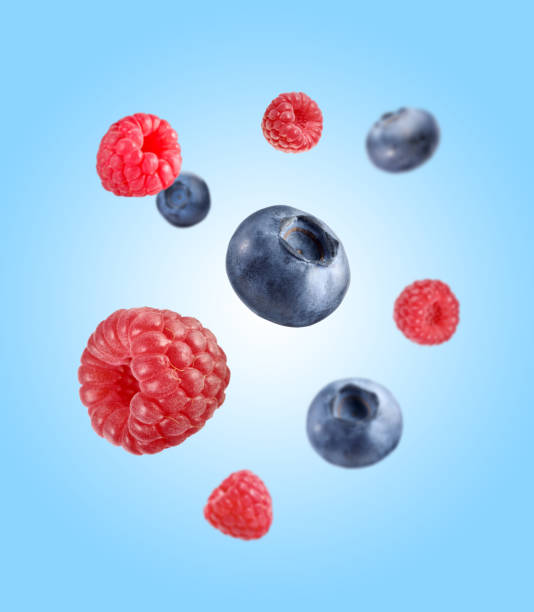 istock Fresh ripe blueberries and raspberries falling on light blue background 1806183890