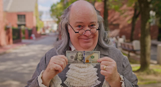 Benjamin Franklin Impersonator Showing Off Hundred Dollar Bill and Suggesting Similarity with Ben Franklin on the Note