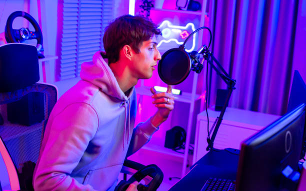 istock Portrait handsome young male game online streamer, caster, smiling, looking at camera, compete games, sitting in room with decorated neon light. Looking at computer. 1806190474