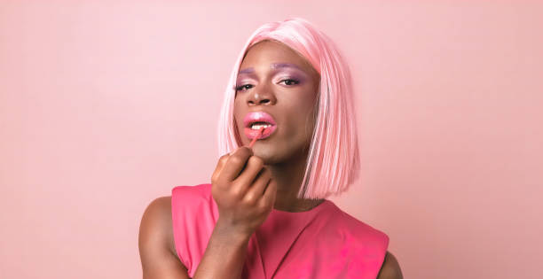 istock Young black transgender applying lip gloss in studio against pink background 1806193732