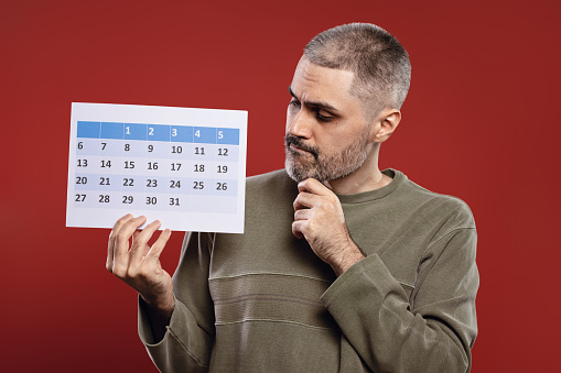 Man holding a paper calendar in one hand