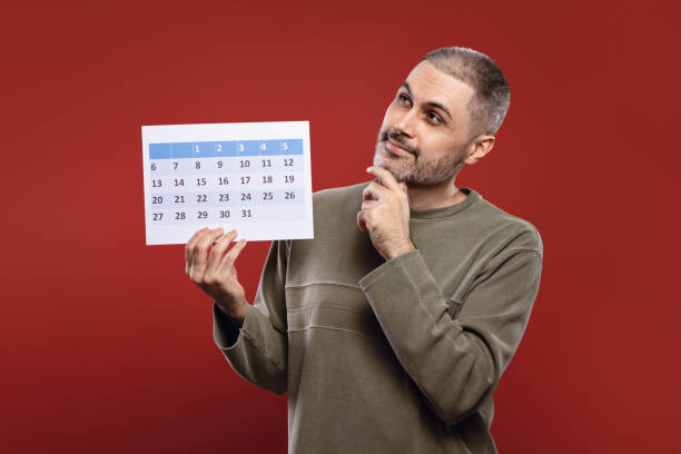 istock Man holding a paper calendar in one hand 1806197012