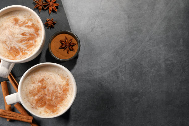 istock Cups of delicious eggnog with anise and cinnamon on grey table, flat lay. Space for text 1806205595