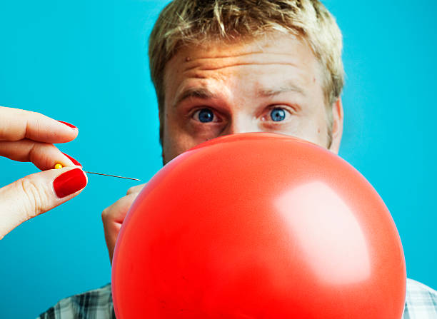 Blonde man blowing up a balloon stock photo