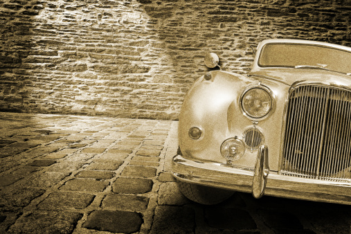 old car on the stone floor in front of a brick wall