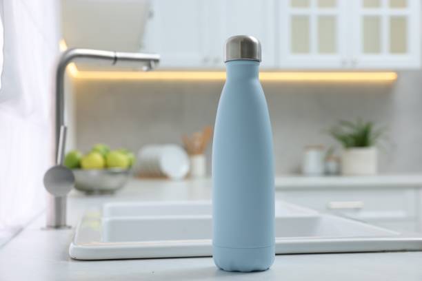 istock Stylish thermo bottle on white countertop in kitchen. Space for text 1806218980