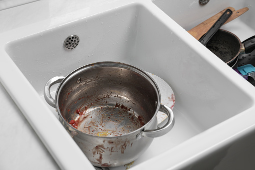 Sink with dirty metal pot in kitchen