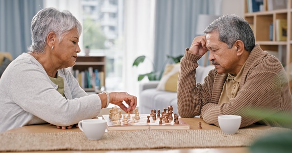 Senior couple, chess and thinking in home, retirement and challenge with strategy, moving and ideas. Elderly woman, old man and board game with king, queen or knight for contest, relax or strategy