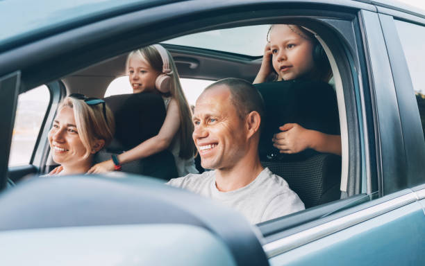 istock Happy smiling young couple with two daughters inside car during auto trop. They are smiling, and laughing during a road trip. Family values, tatraveling, automotive industry concept. 1806247782