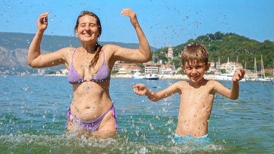 Photo of two cute brothers and their parents paddling on the lake,  and enjoying summer days far from the hustle of the city.