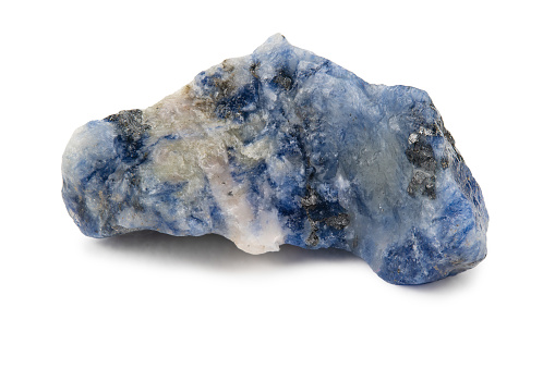 A piece of uncut bluish sodalite with white veins. Isolated on a white background.