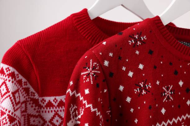 istock Christmas sweaters hanging on rack against light background, closeup 1806281386