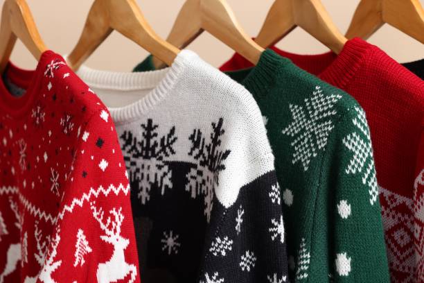 istock Different Christmas sweaters hanging on rack against beige background, closeup 1806281934