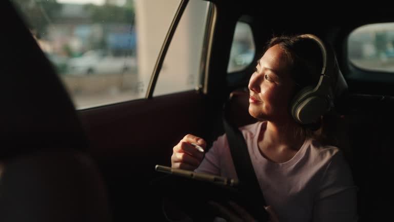 Woman using digital tablet in backseat of car.