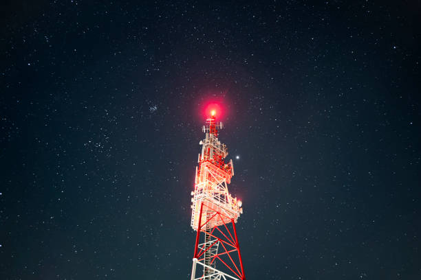 Looking up at illuminated tower with a starry night sky. Tower Antenna Telecommunication Cell Phone, Radio Transmitters of Cellular 5g 4g Mobile Phone.