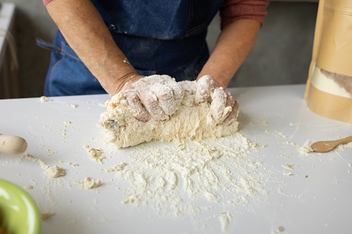 Kneading dough. Male chef in kitchen chef's apron spraying flour over dough