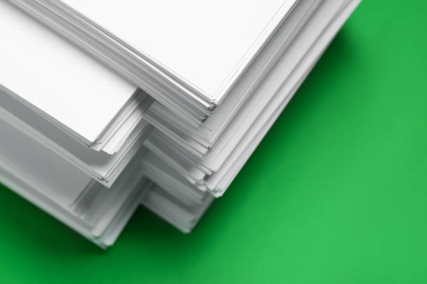 istock Stack of white paper on green background, closeup. Space copy text 1806306289