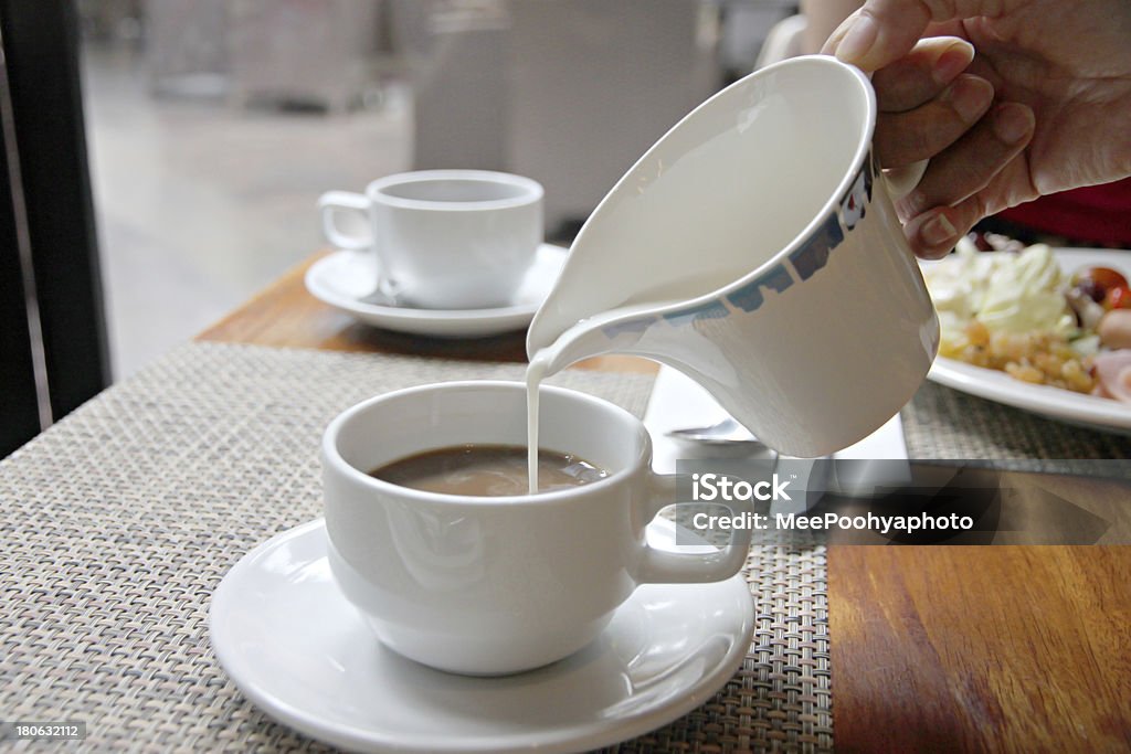 Verter la leche en una taza de café. - Foto de stock de Afrodescendiente libre de derechos
