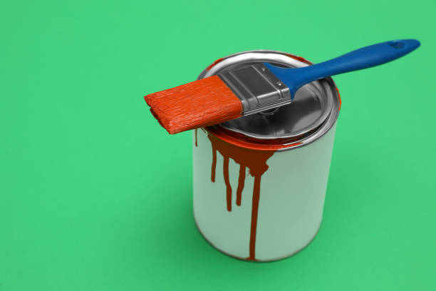 istock Can of orange paint and brush on green background. Space for text 1806326314