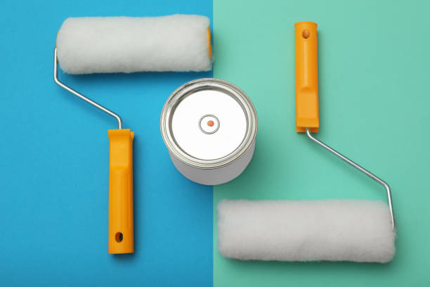 istock Can of orange paint and roller brushes on color background, flat lay 1806326345