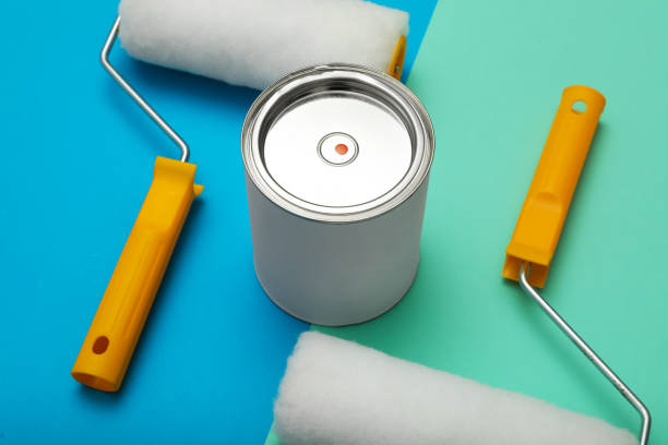 istock Can of orange paint and roller brushes on color background 1806326353