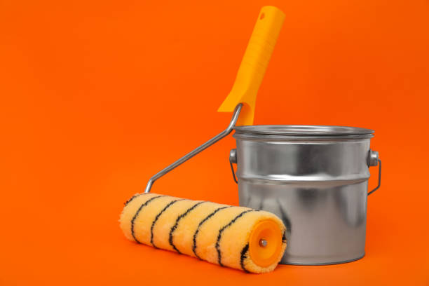 istock Can of orange paint and roller brush on color background. Space for text 1806326864