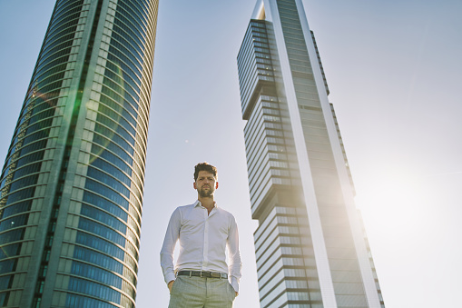 young caucasian businessman posing with office buildings in background. copy space for text.