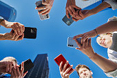 Group of business workers smiling happy and confident. Standing on a circle with smile on face using smartphone together at the office.