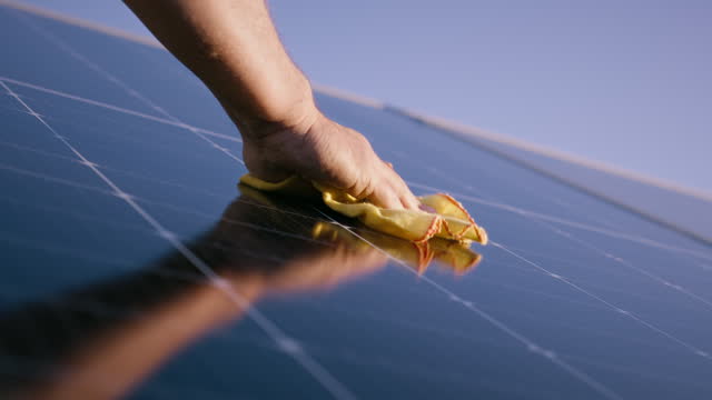 Hand cleaning solar panel on roof with cloth, maintenance and renewable energy or green electricity. Engineer, closeup and wash photovoltaic for dust, dirt and improve performance or power production