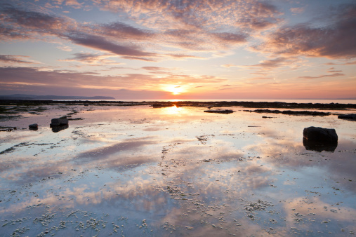 Beautiful colors of the sunset are reflected in this tidal pool during low tide at Kilve Beach in somerset.