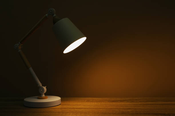 istock Stylish modern desk lamp on wooden table at night, space for text 1806358585