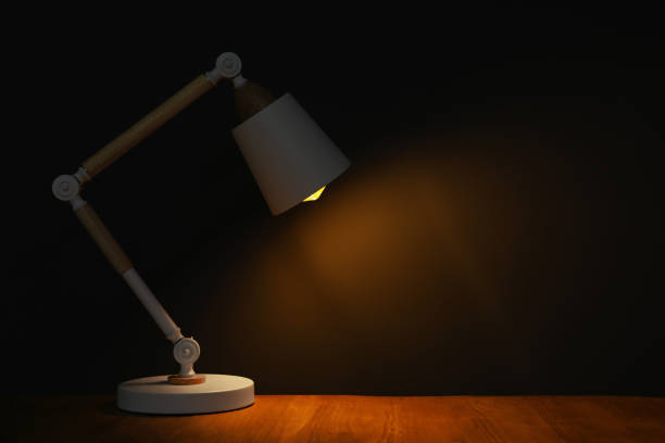 istock Stylish modern desk lamp on wooden table at night, space for text 1806358982