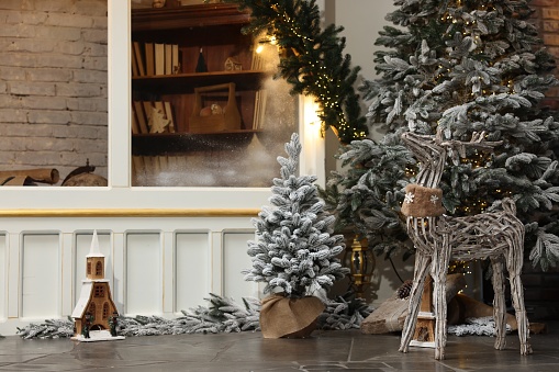Beautiful Christmas trees, deer and other festive decor indoors, space for text. Interior design