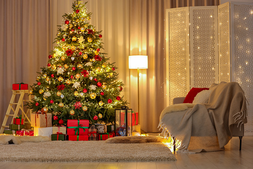 Beautifully wrapped gifts under Christmas tree in living room. Festive interior design